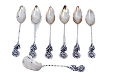 Conjunto de seis colheres de café e pá de açúcar com malmequeres e cabos torcidos.